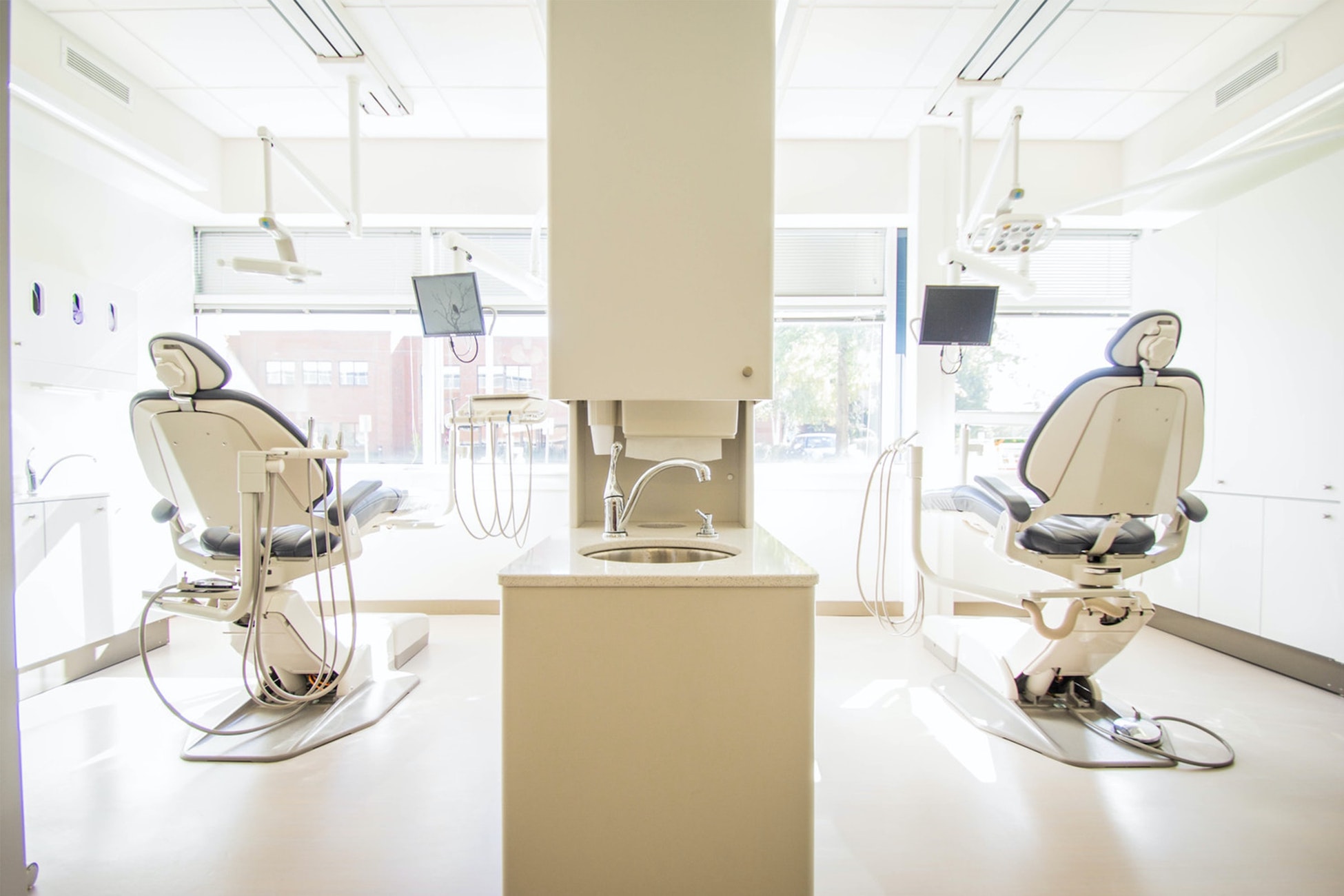 Two empty white dentist chairs. Should dental practices implement no-show fees? 